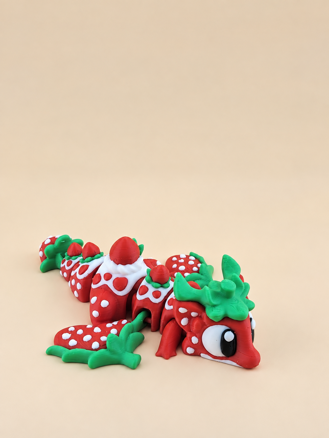 Articulated Strawberry Dragon with red and white body and green leaf details, viewed from the front