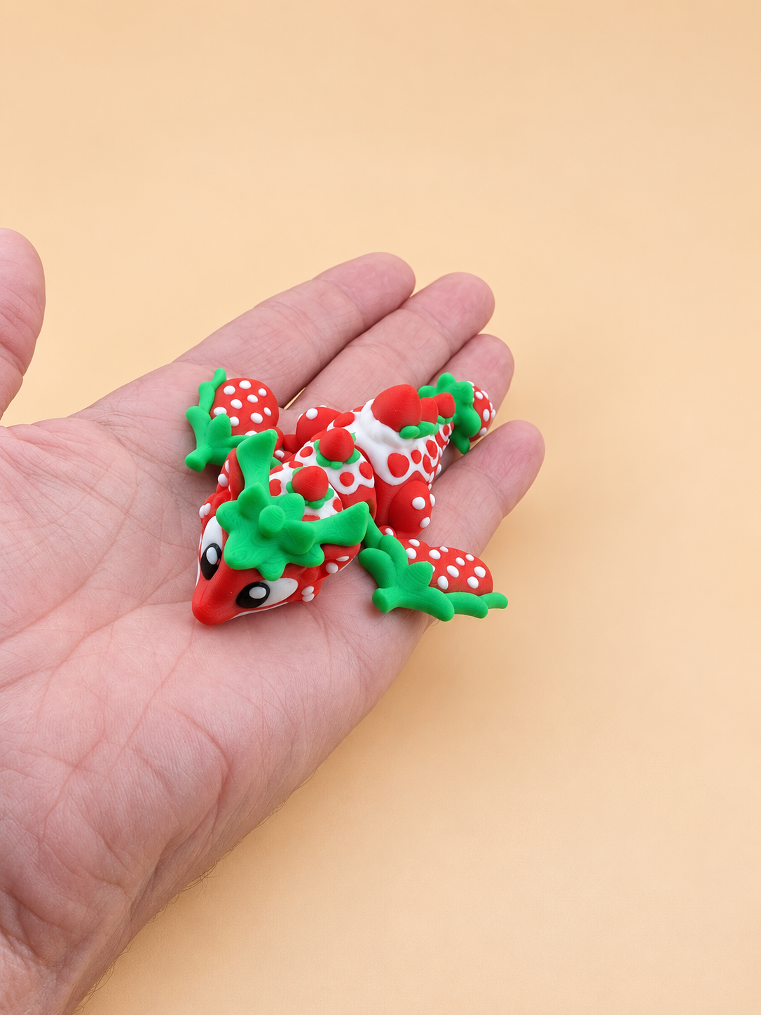 Small articulated Strawberry Dragon resting in a hand to show its size